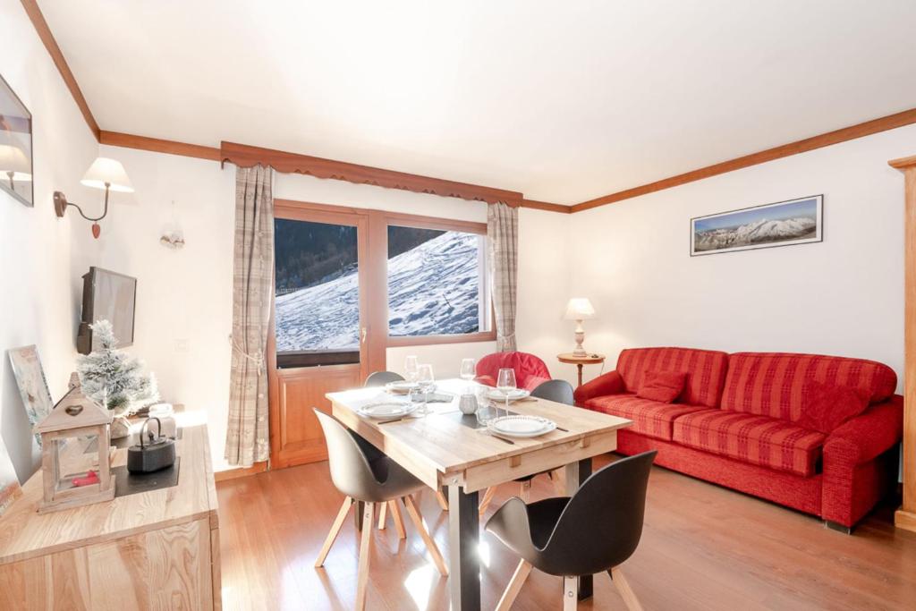 a living room with a red couch and a table at Family Apt With Superb View On The Mont Blanc in Les Houches
