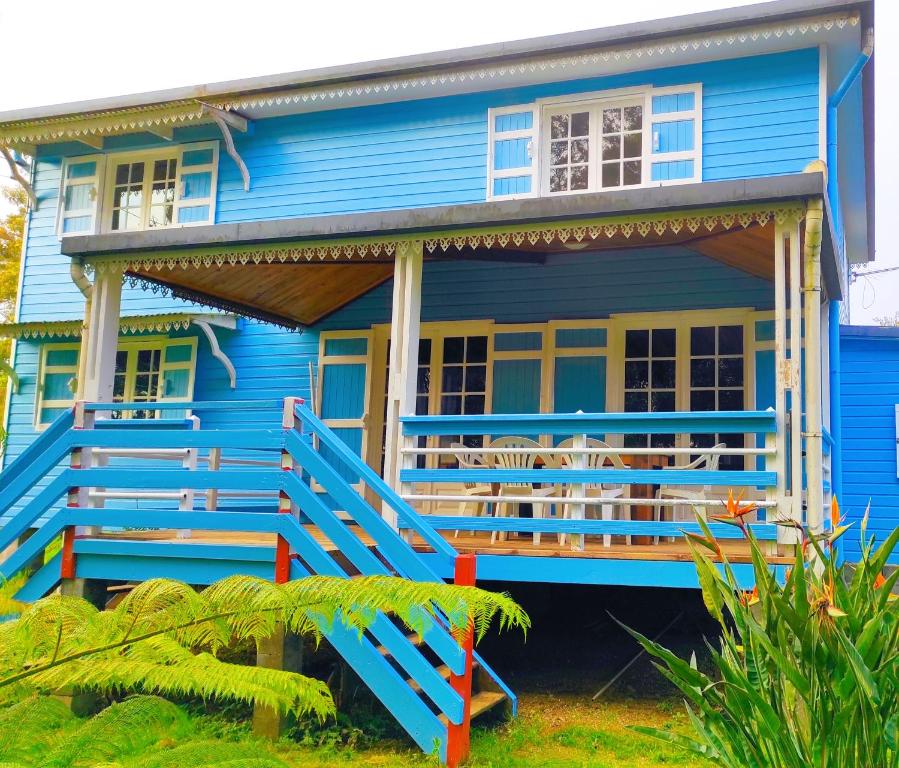 ein blaues Haus mit einer Veranda und einem Balkon in der Unterkunft La Villa Des O, sentier Grand Bassin in La Plaine des Cafres