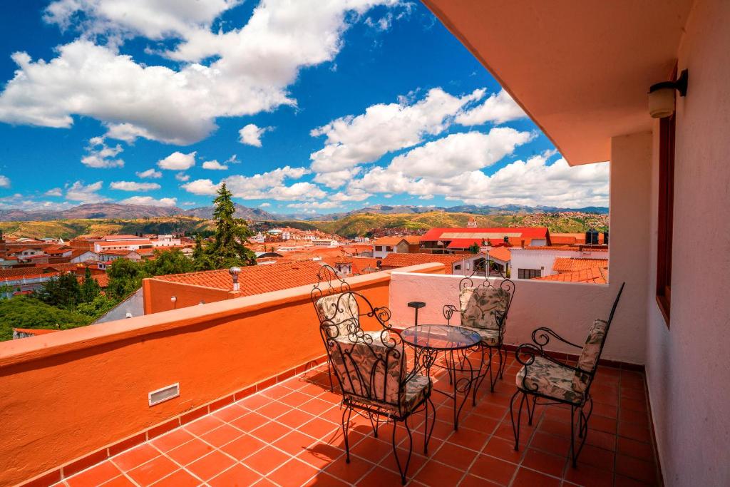 Un balcón con 2 sillas y una mesa con vistas. en Hotel Villa Antigua en Sucre