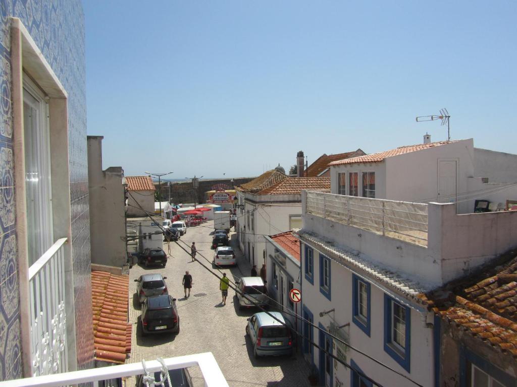 a city street with cars and people walking down the street at D. Antonia in Peniche