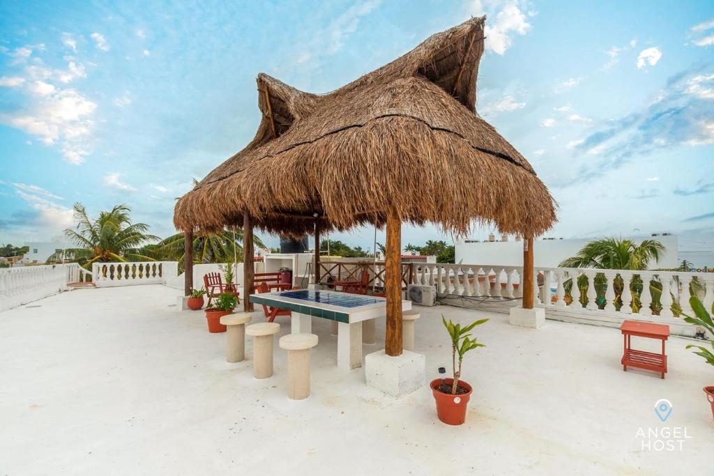 a table and a straw umbrella on the beach at Malecon Beach House in Progreso 1 block from beach in Progreso