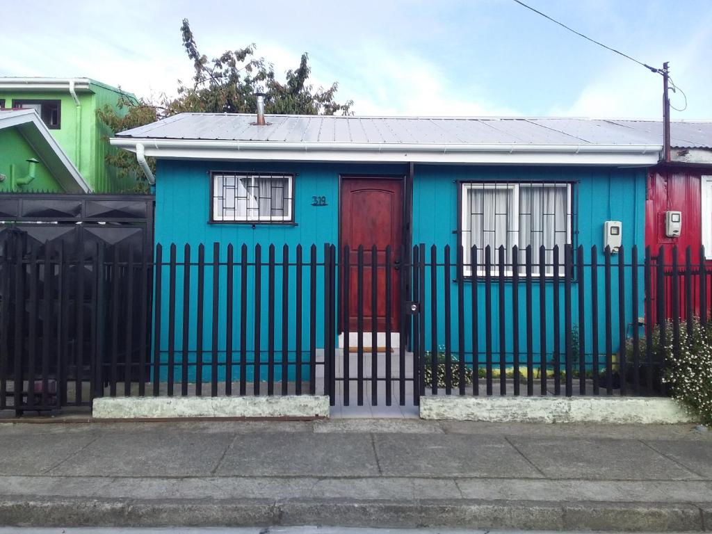 a blue house with a red door and a fence at Casa Pali in Puerto Montt