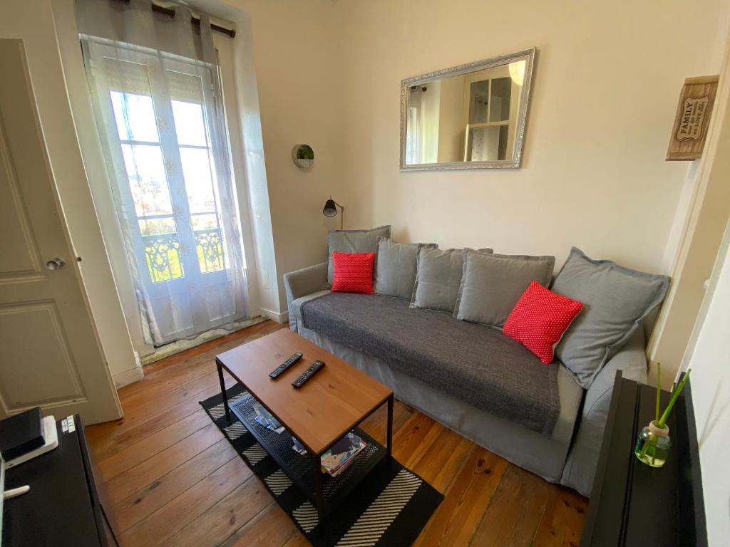 salon z szarą kanapą i czerwonymi poduszkami w obiekcie Manjericos House w Lizbonie