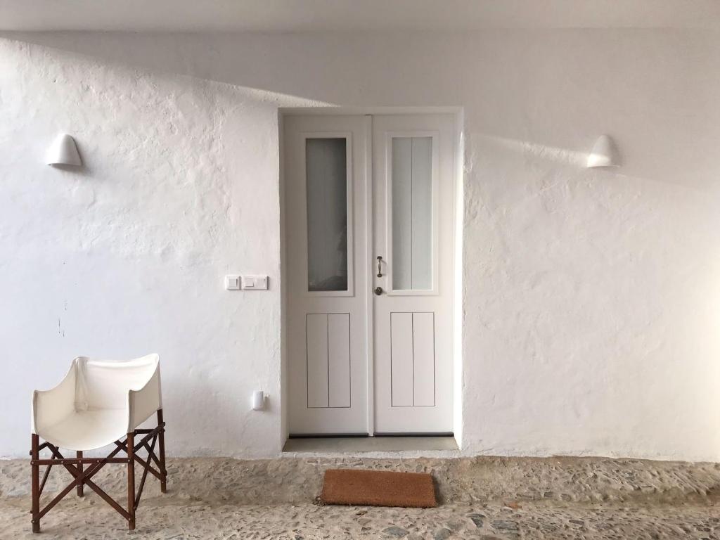 um quarto branco com uma porta branca e uma cadeira em Estudio do Loureiro na Vidigueira