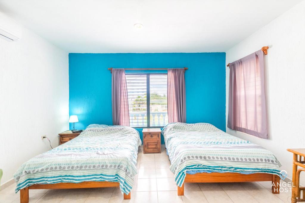 two beds in a room with a blue wall at Malecon Beach House in Progreso 1 block from beach in Progreso