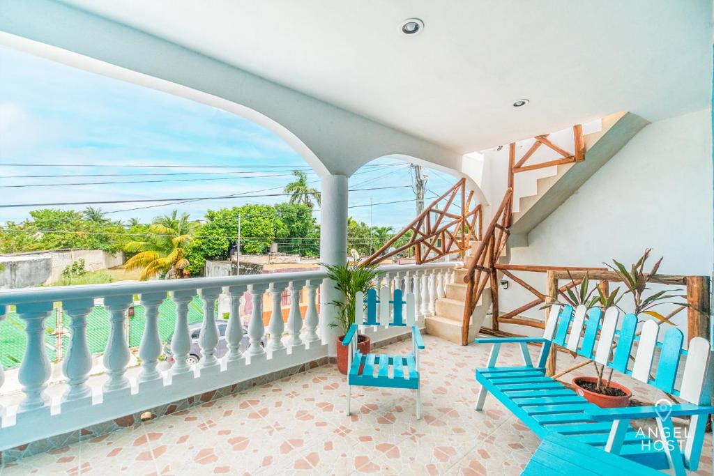 a balcony with two blue chairs and a staircase at Malecon Beach House in Progreso 1 block from beach in Progreso