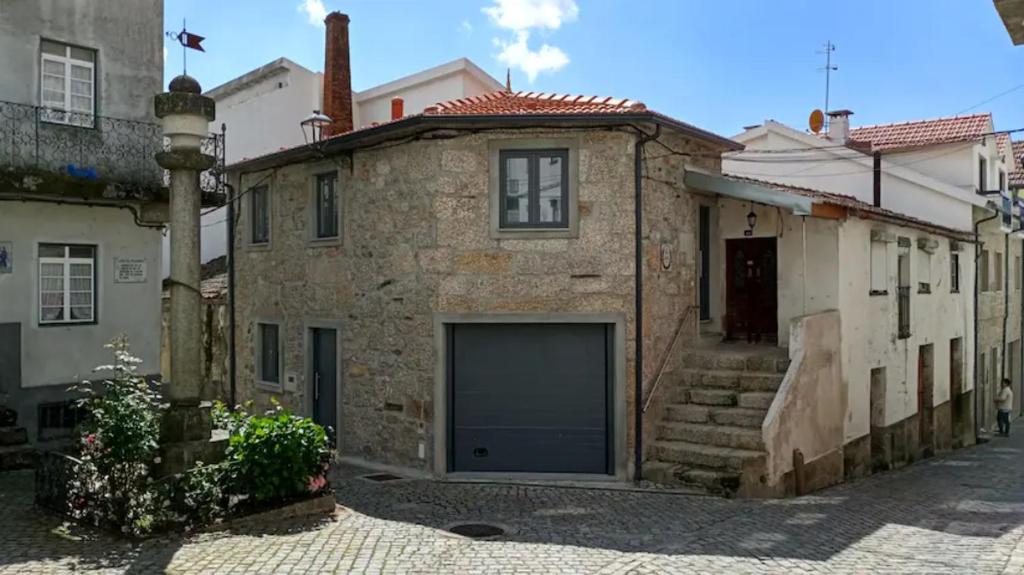 a stone house with a garage in a street at Casa do Pelourinho - T1 in Loriga