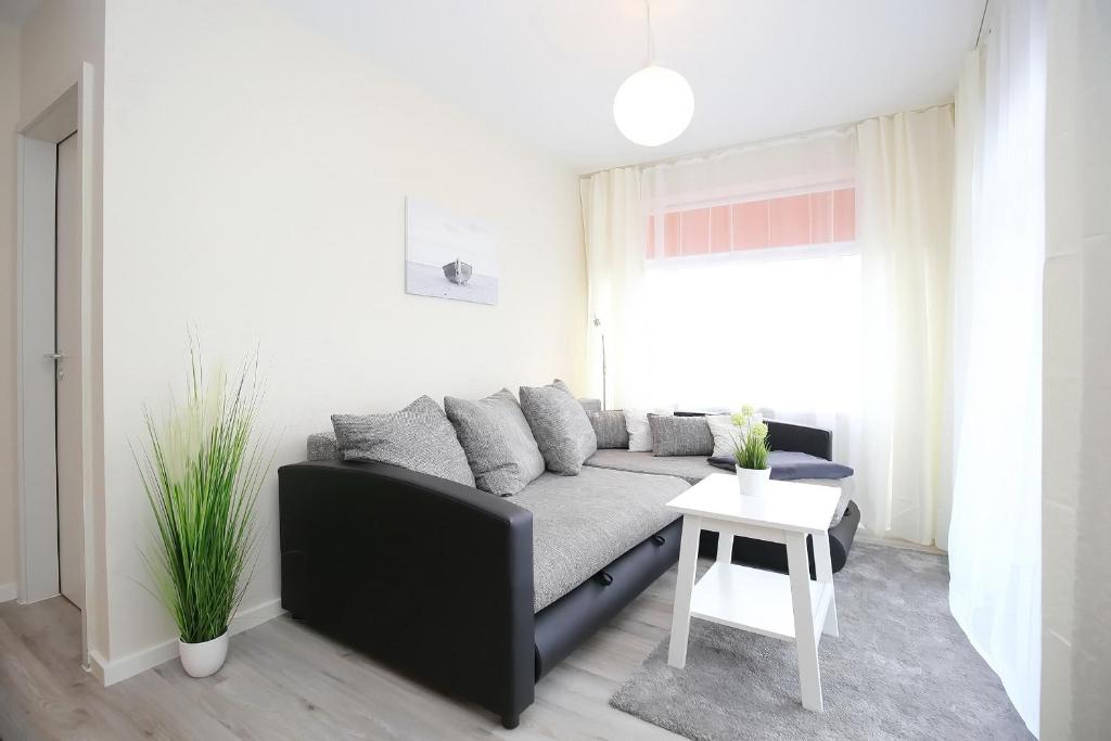 a living room with a black couch and a table at Haffblick Wohnung 43 in Boltenhagen