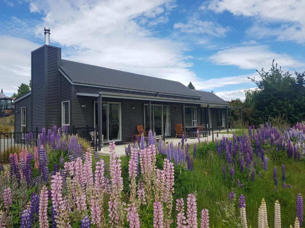 a house with a field of purple flowers in front of it at Macaulay House in Lake Tekapo