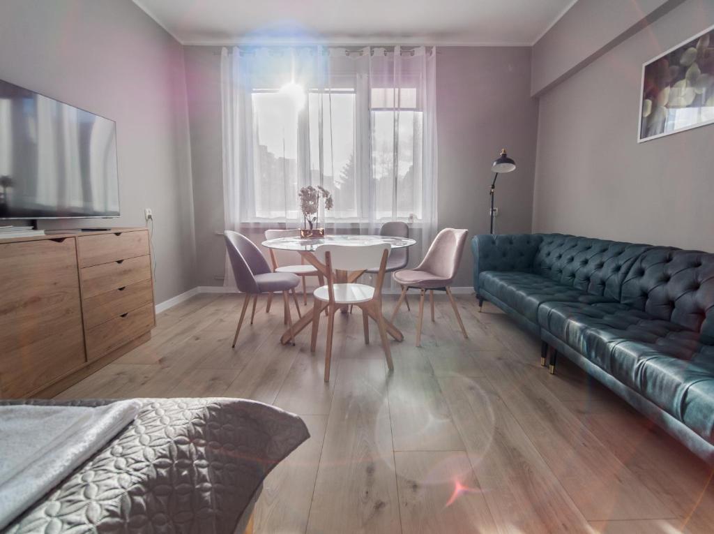 uma sala de estar com uma mesa e um sofá verde em Krosna Street Apartament em Gdansk