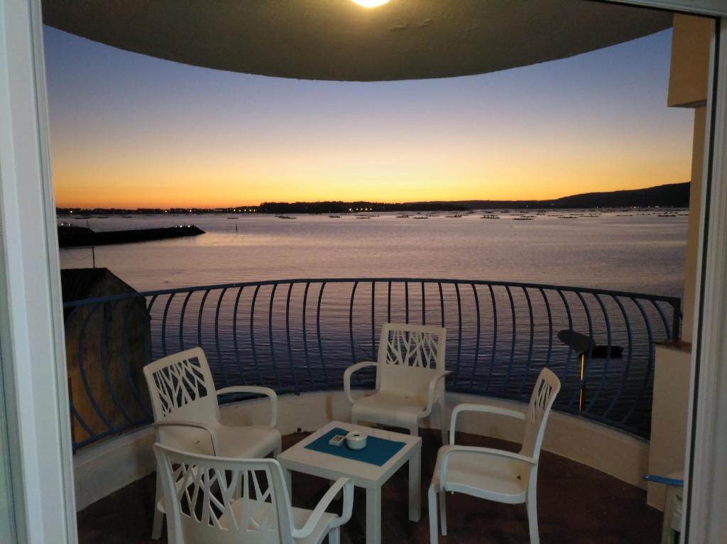 uma varanda com mesa e cadeiras e um pôr-do-sol em Apartamentos Poniente em Vilanova de Arousa