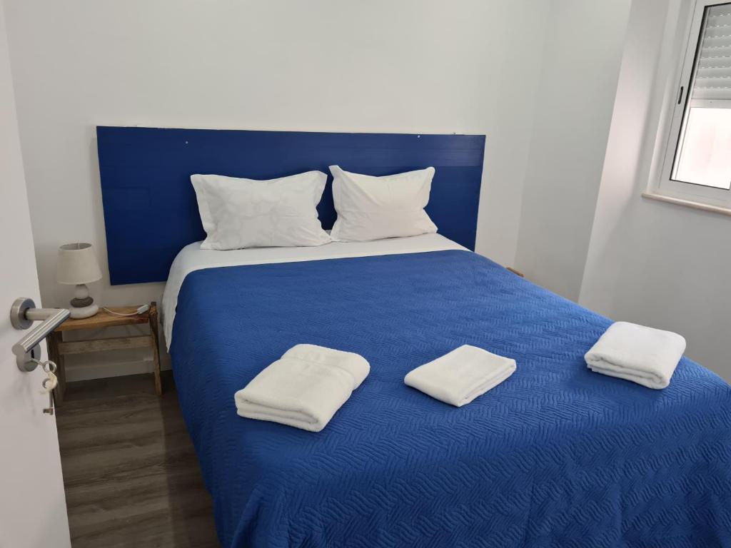 Una cama azul con dos toallas blancas. en Casa do Mestre, en Setúbal