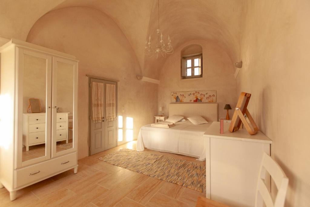 a bedroom with a white bed and a white cabinet at Castelli Loggia in Emporio Santorini