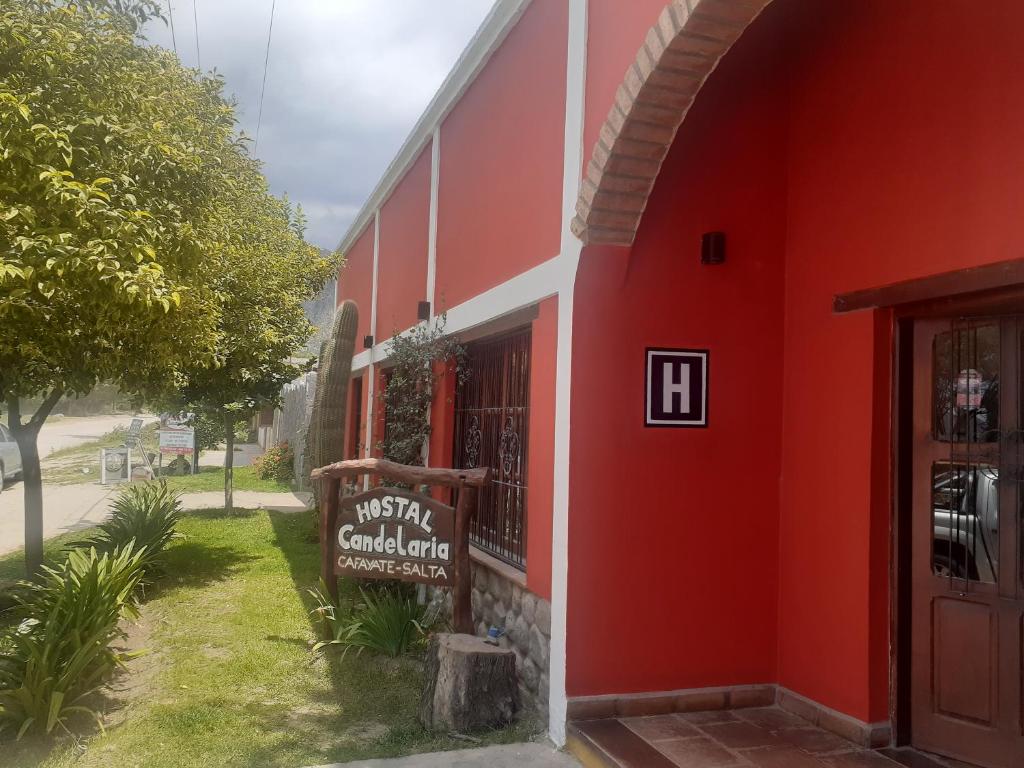 ein rotes Gebäude mit einem Schild davor in der Unterkunft Hostal Candelaria in Cafayate