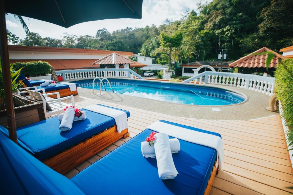 a swimming pool with two blue chairs and an umbrella at Hotel Villabosque Eco Boutique in Manuel Antonio