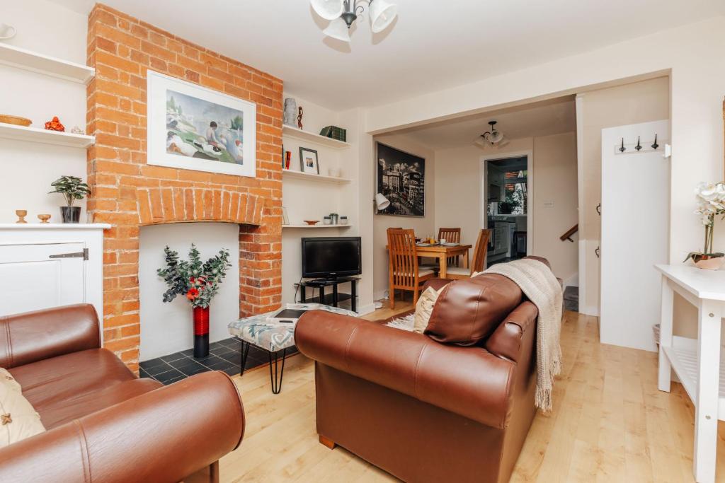 a living room with leather furniture and a brick wall at Honeysuckle terrace in Henley on Thames