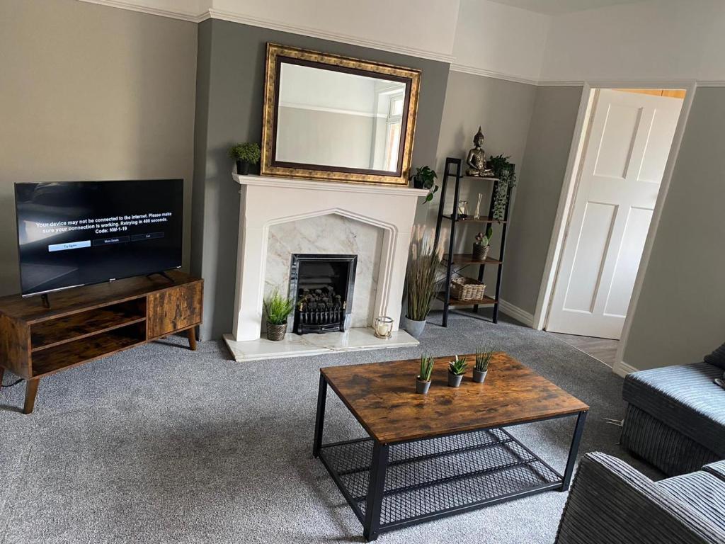 uma sala de estar com uma lareira com um espelho e uma televisão em Chatsworth - Large Apartment Near Newcastle City Centre em Saint Peters