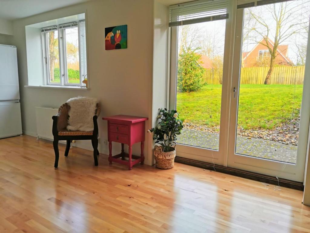 uma sala de estar com uma cadeira, uma mesa e portas de vidro deslizantes em 300meter walk to LEGO house - 70m2 apartment with garden em Billund