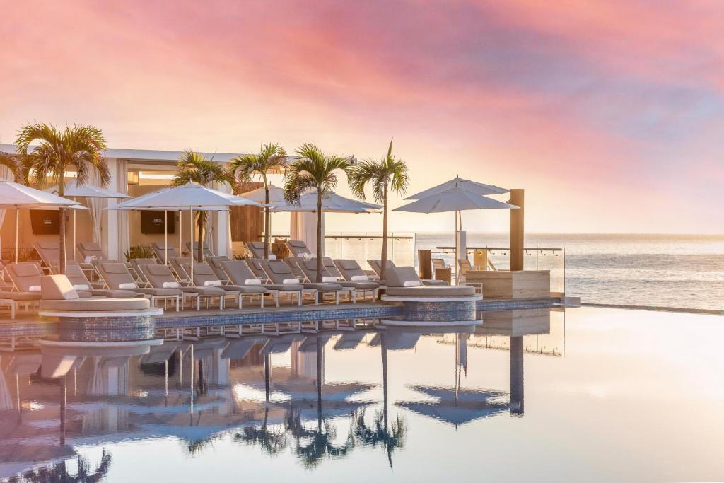 サン・ホセ・デル・カボにあるLe Blanc Spa Resort Los Cabos Adults Only All-Inclusiveの海のそばのプール(椅子、パラソル付)