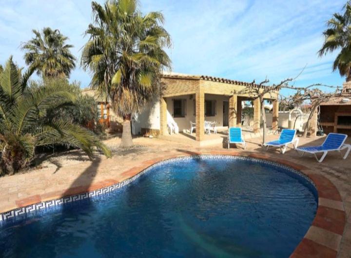 a swimming pool in front of a house with palm trees at Holiday Home Paquita SB in Riumar