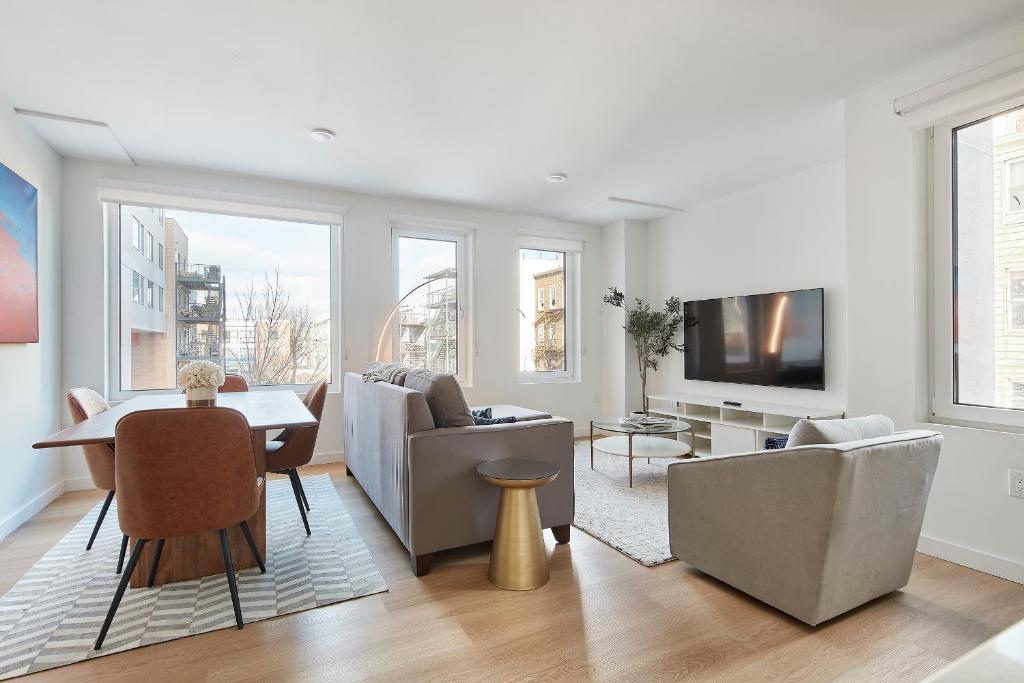 een woonkamer met een tafel en stoelen en een televisie bij Harmony Lofts on Jackson 2 in Hoboken