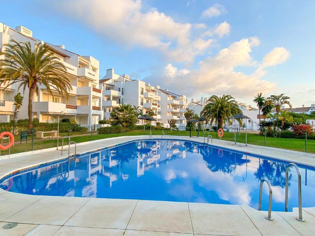 basen przed budynkiem z palmami w obiekcie Golf Gardens Miraflores - Bright and spacious apartment w mieście Mijas Costa