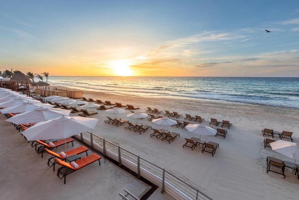 einen Strand mit Liegestühlen und Sonnenschirmen und dem Meer in der Unterkunft Beach Palace - All Inclusive in Cancún