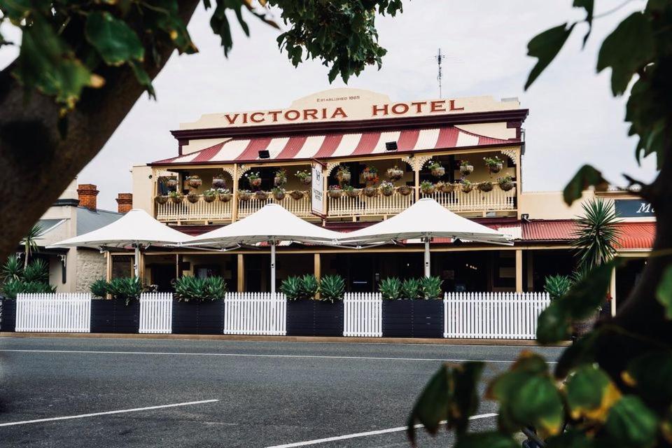 a hotel with white umbrellas in front of it at Victoria Hotel Strathalbyn in Strathalbyn