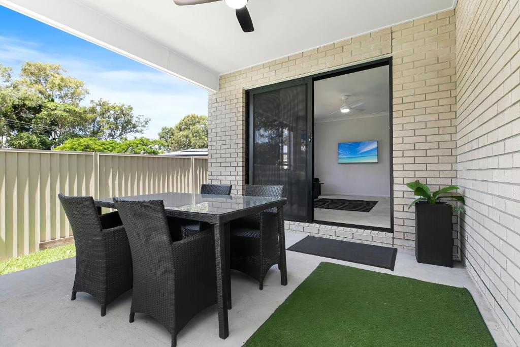 a patio with a black table and chairs at Bribie Getaway Villa in Bongaree