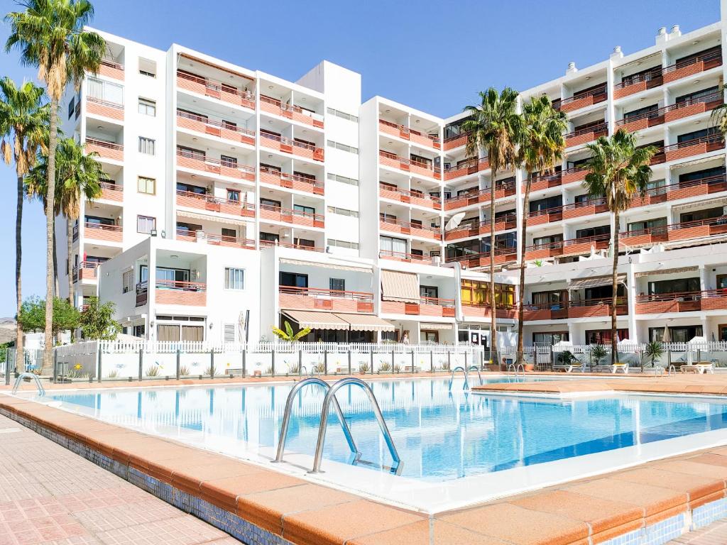 una piscina frente a un gran edificio de apartamentos en Cozy Beach Holiday Home in Playa del Ingles, en Playa del Inglés