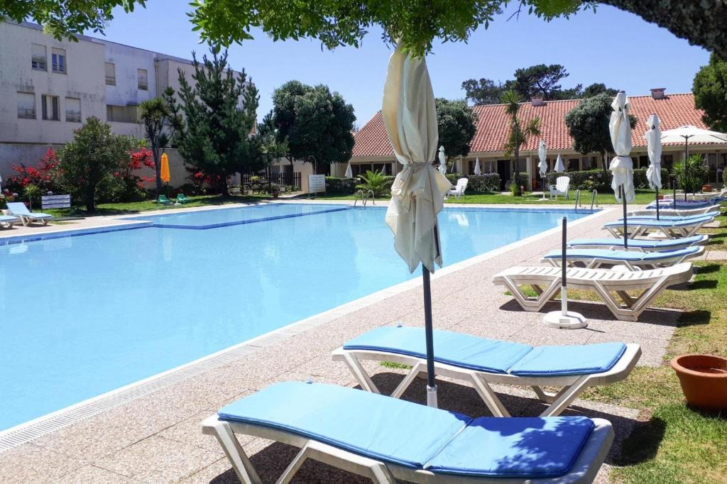 a group of chairs and an umbrella next to a swimming pool at Holiday resort Clube Pinhal da Foz, Esposende, Studio for 2 pers in Esposende