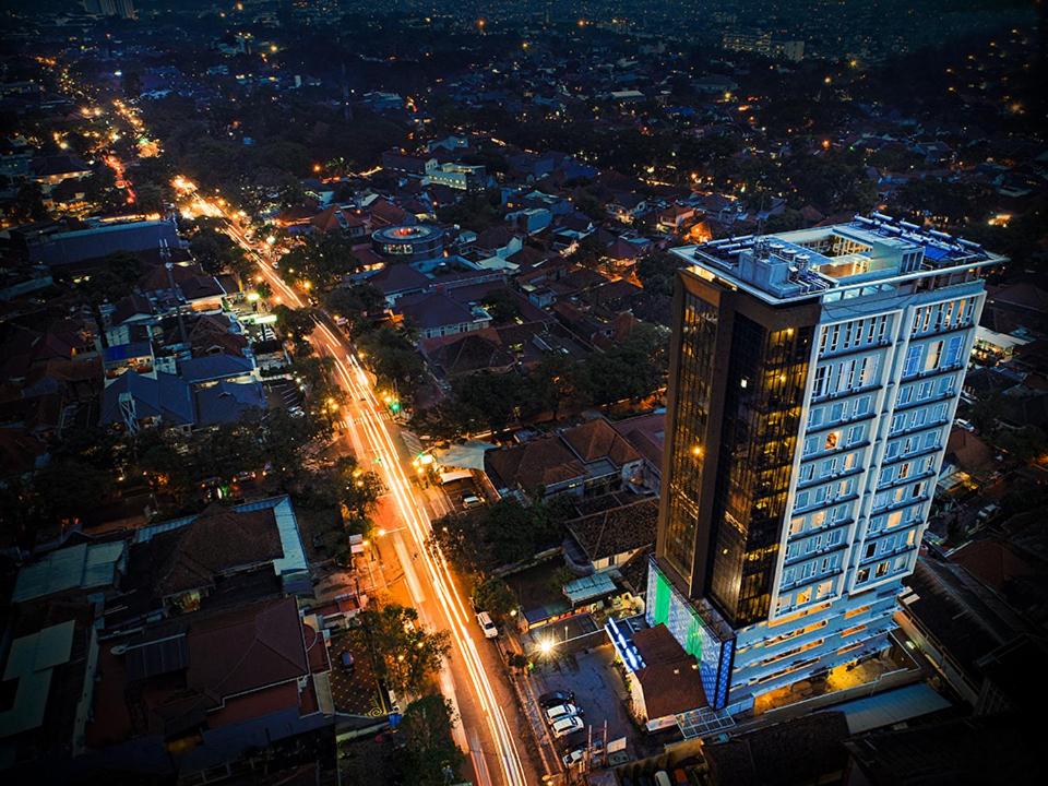 a tall building with lights on a city at night at Grand Tebu Hotel in Bandung