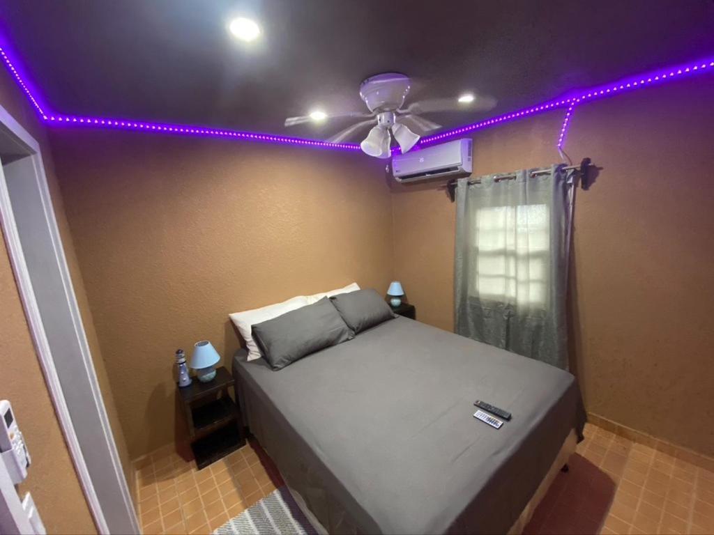 a bedroom with a bed with a ceiling fan and purple lights at Bahia Azul Apartment in Six Huts