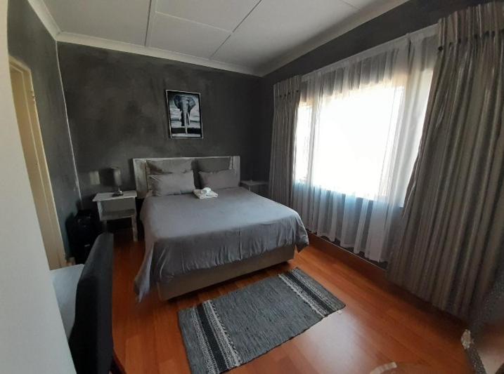 a bedroom with a bed and a large window at The Private and Cosy Guest House 1 in Germiston