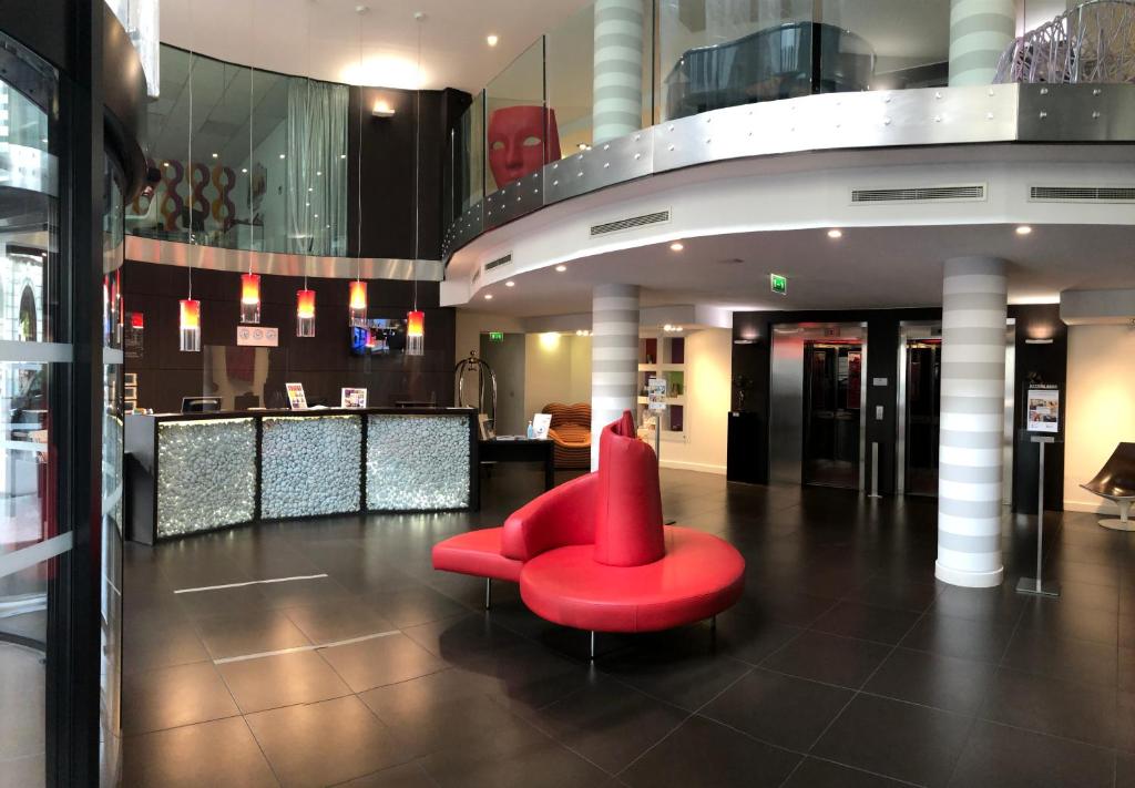 a red chair sitting in the middle of a lobby at Le Rex Hôtel in Tarbes