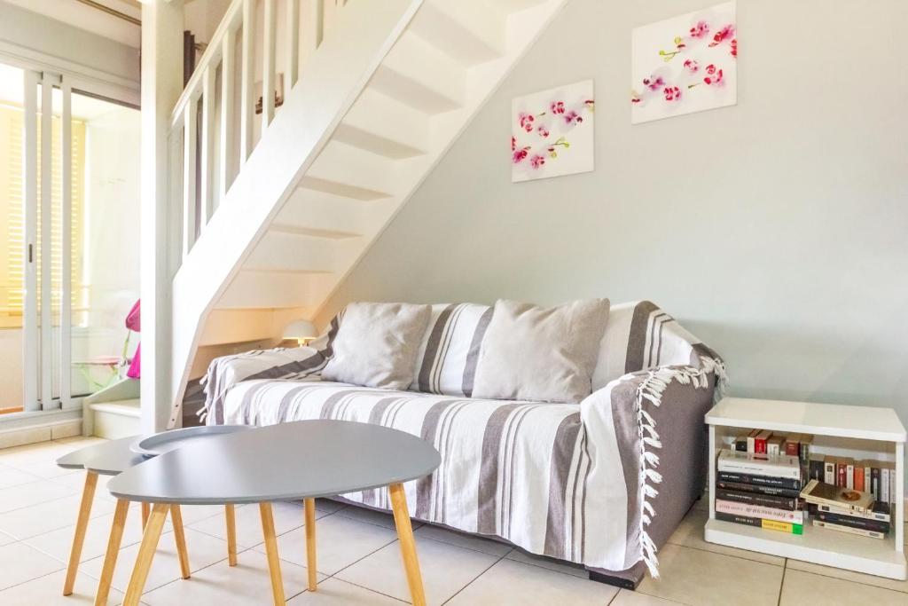 ein Wohnzimmer mit Sofa und Tisch in der Unterkunft Purple - Duplex cosy en plein cœur de l'Hermitage, proche du lagon in L'Ermitage-Les-Bains