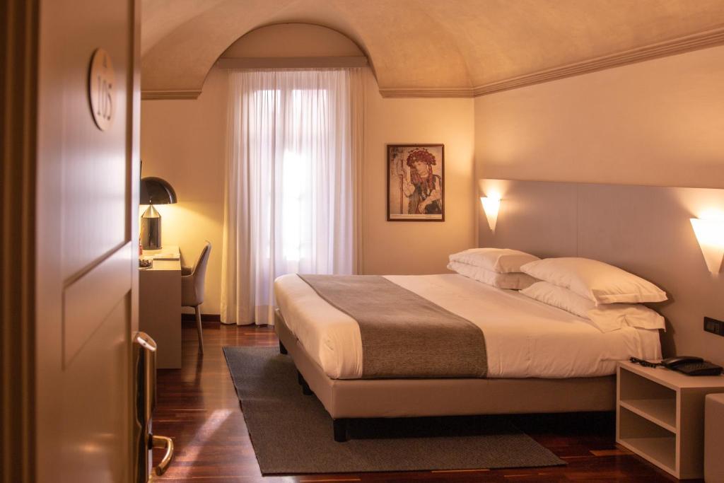 Un dormitorio con una cama grande y una ventana en Hotel Boutique Antiche Mura en Saluzzo