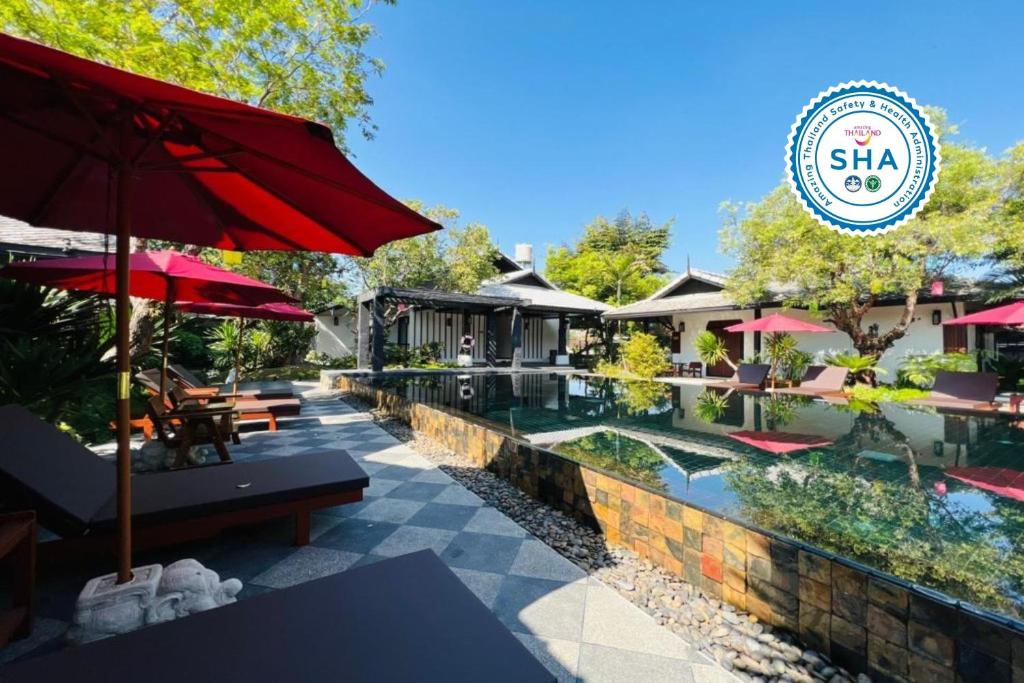 a resort with a pool and a red umbrella at Na Mantra Resort in Chiang Mai