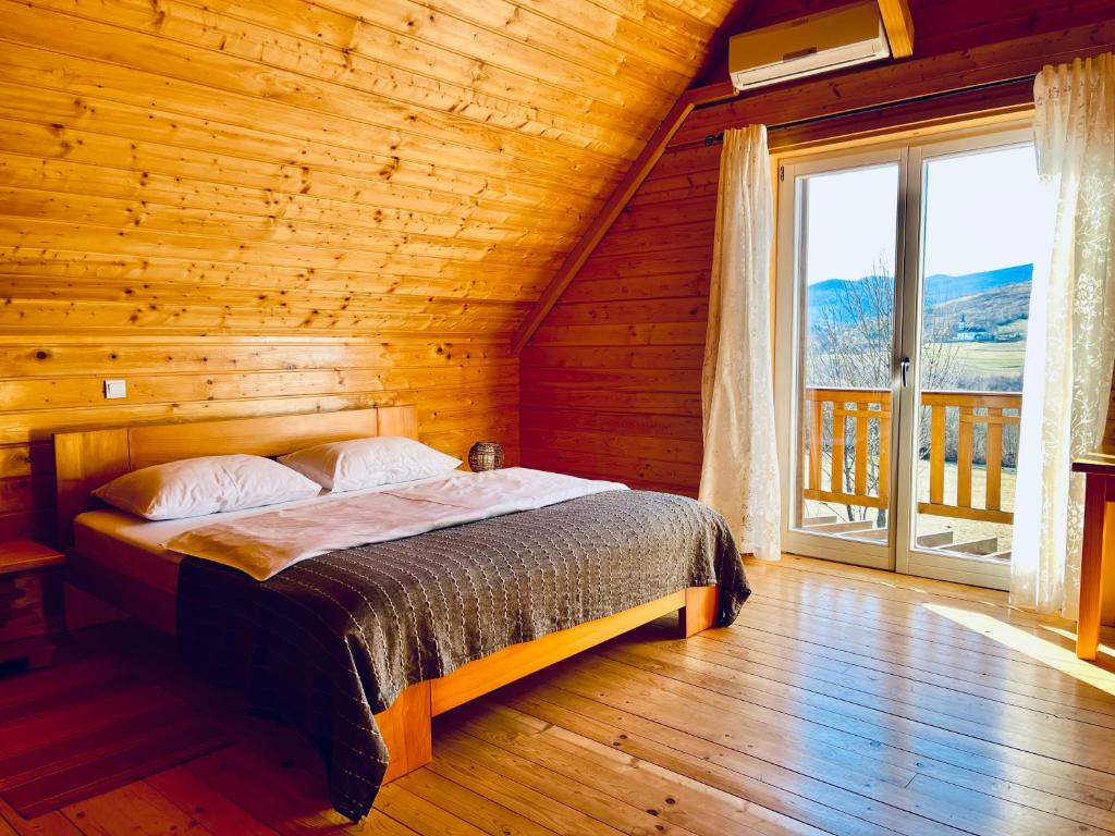 a bed in a wooden room with a large window at Holiday Homes Vita Natura in Rakovica