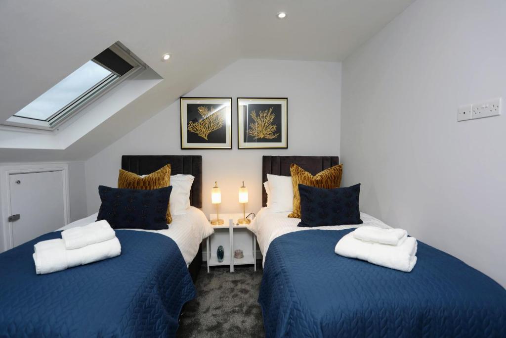 ein Schlafzimmer mit zwei Betten mit blau-weißer Bettwäsche in der Unterkunft Aisiki Apartments at Stanhope Road, North Finchley, Airconditioned 3-Bedroom and 2-Bathroom, Pet-Friendly Duplex Flat, King or Twin Beds, with Free Wi-Fi in Finchley