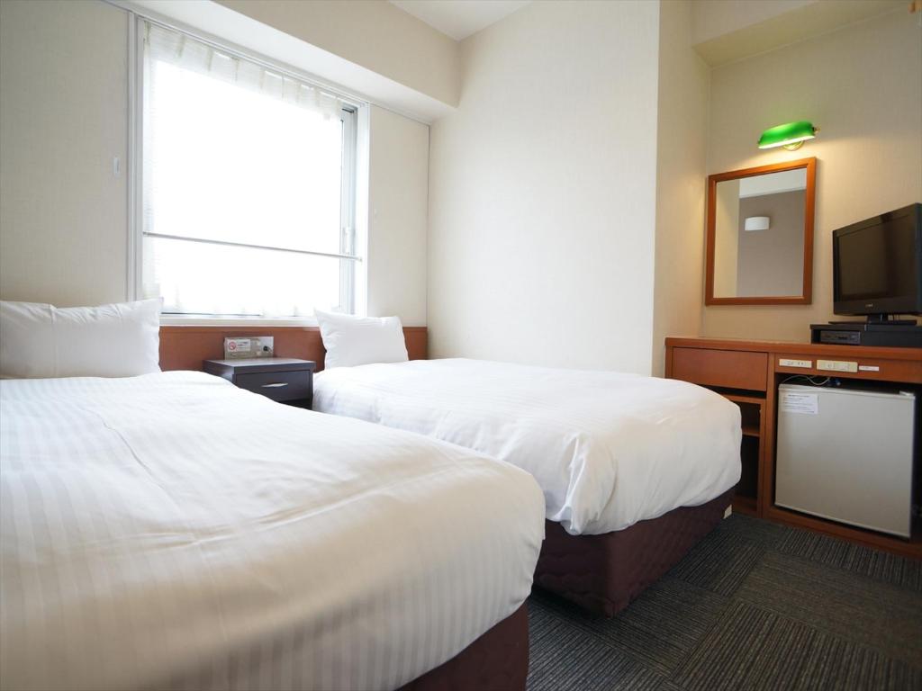 熊本市にあるジーアールホテル銀座通のベッド2台とテレビが備わるホテルルームです。