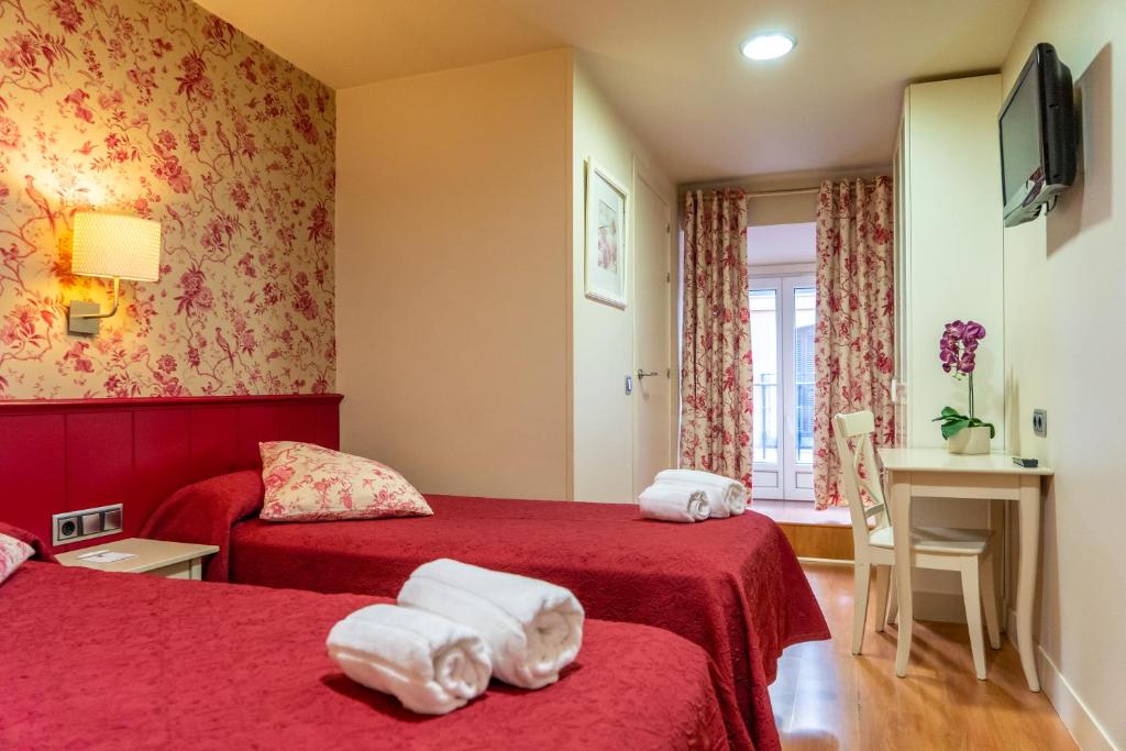 una camera d'albergo con due letti con lenzuola rosse di Hostal Matheu a Madrid