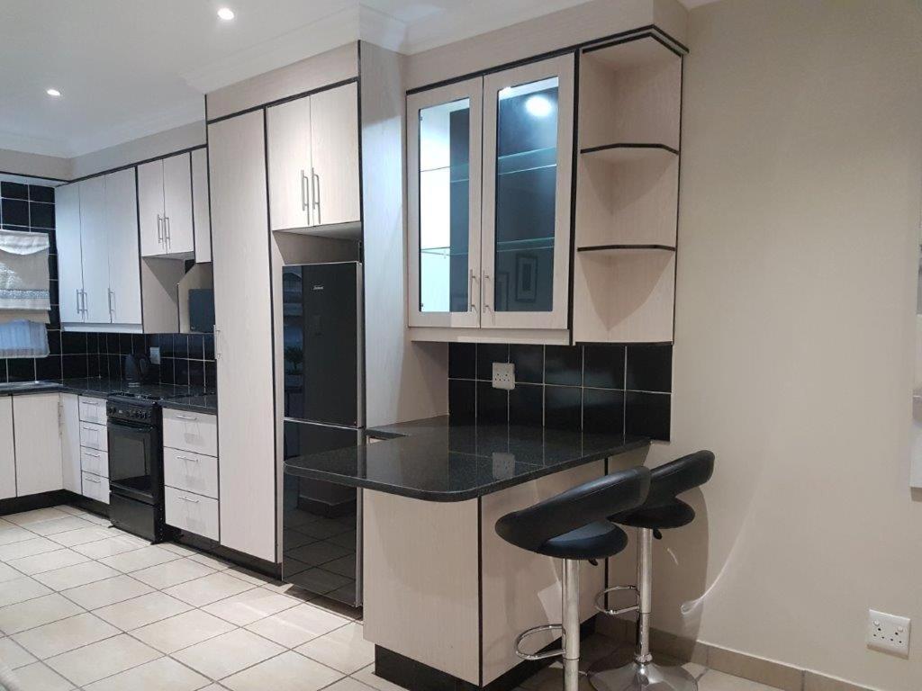 uma cozinha com armários brancos e um balcão preto em Genie's Nest Ooie 3 em Pretoria