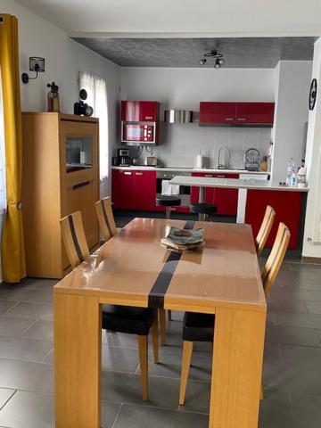a wooden table and chairs in a kitchen with red cabinets at Logement calme et spacieux avec terrasses in Le Havre