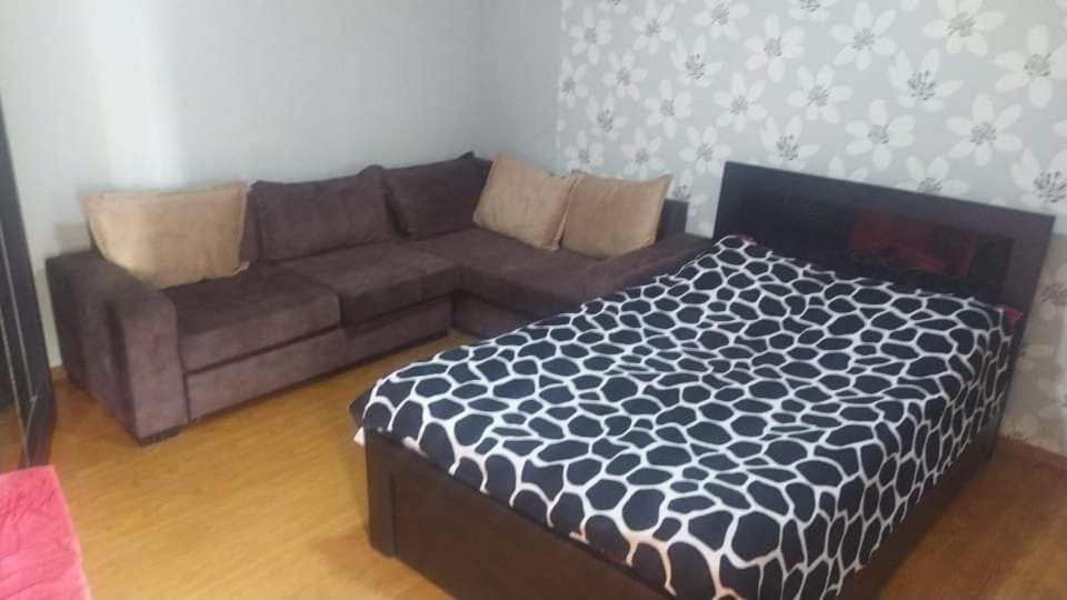 a living room with a brown couch and a bed at Lana Apartment in Tbilisi City