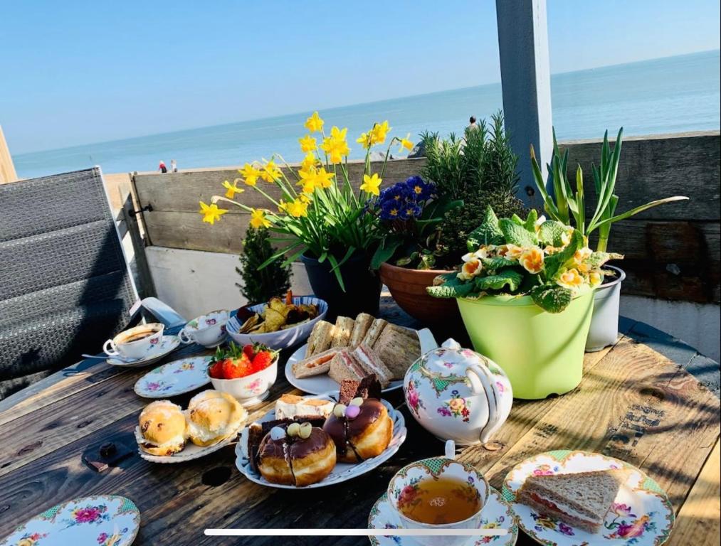 a table with plates of food on a table with the beach at The beach cottage in Folkestone