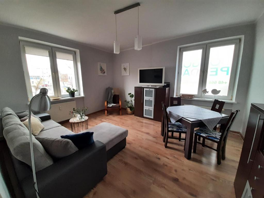 ein Wohnzimmer mit einem Sofa und einem Tisch in der Unterkunft Apartament Oksywska Przystań in Gdynia