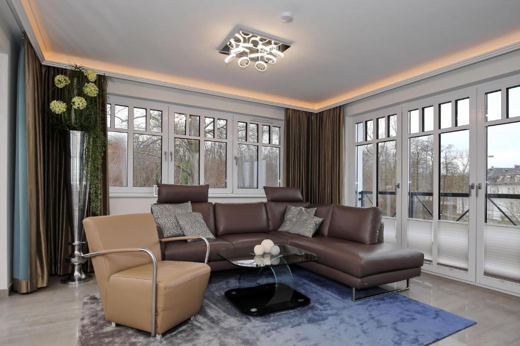 a living room with a brown couch and windows at Linden-Palais Wohnung 33 in Heiligendamm