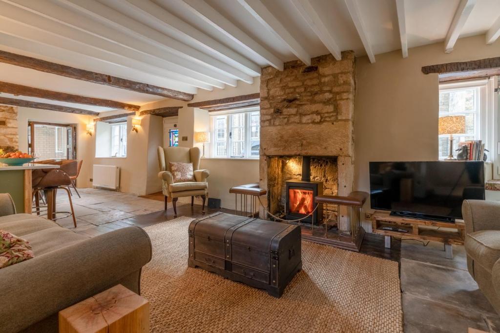 a living room with a fireplace and a tv at Farthingdales in Burford