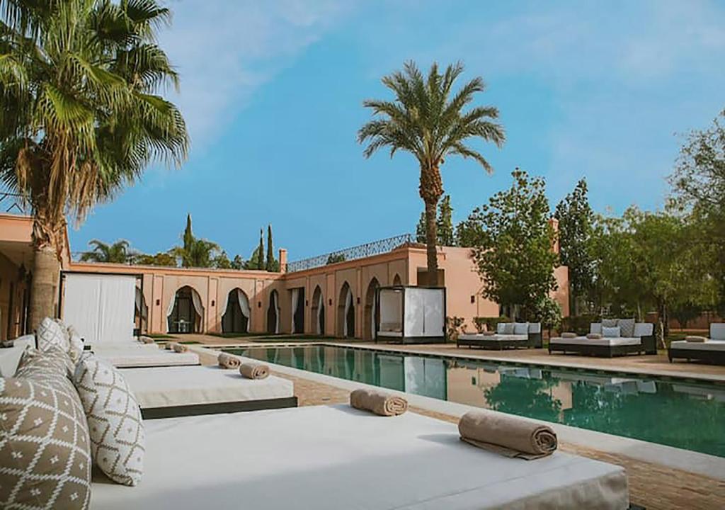ein Pool mit Palmen und ein Gebäude in der Unterkunft DAR JMEL in Marrakesch